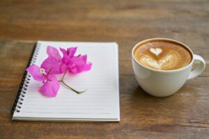 Coffee, a note pad, and a deep pink spring of bougainvillea flowers.