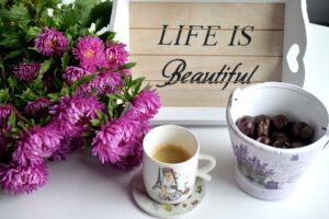 coffee and bright pink flowers plus a sign that says, "life is beautiful."