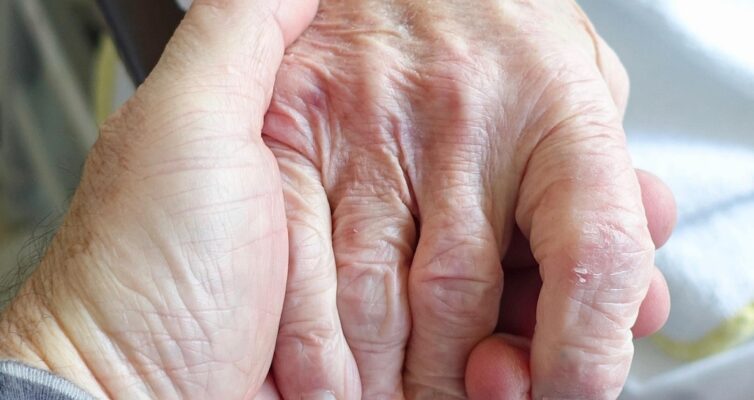 Person holding an elderly woman's hand demonstrating compassion and caring